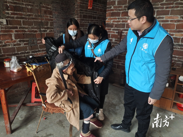 連南瑤族自治縣香坪鎮(zhèn)社工站為困難高齡老人送去御寒棉衣，并幫老人穿上棉衣。